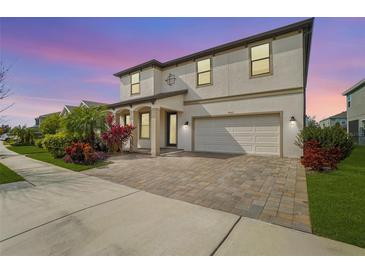 Two-story house with a white facade, paver driveway, and landscaping at 4062 Cadence Loop, Land O Lakes, FL 34638