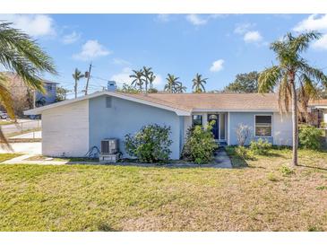 Ranch style home with blue exterior, white accents, and a landscaped yard at 5708 Bayshore Dr, Seminole, FL 33772
