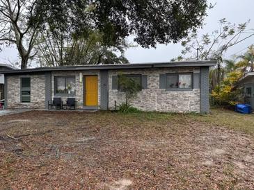 Ranch-style home with stone facade and yellow door at 7011 Conifer Dr, Tampa, FL 33637