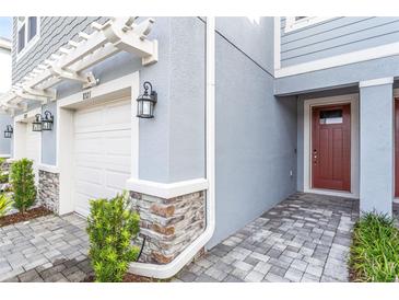 Exterior view of a townhome with a red door and gray siding at 8321 Wildflower Glen Ave, Odessa, FL 33556