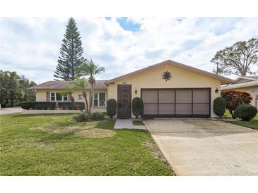 House exterior featuring a well-maintained lawn and attached garage at 102 Stafford Dr, Palm Harbor, FL 34684