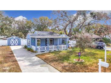 Charming blue house with a white picket fence, landscaping, and a long driveway at 1447 Santa Anna Dr, Dunedin, FL 34698