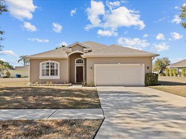 Tan one-story house with a two-car garage and well-manicured lawn at 2309 Cross Tee Ct, Brooksville, FL 34604