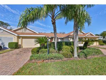 Tan colored exterior, two-car garage, and lush landscaping at 2405 New Haven Cir, Sun City Center, FL 33573