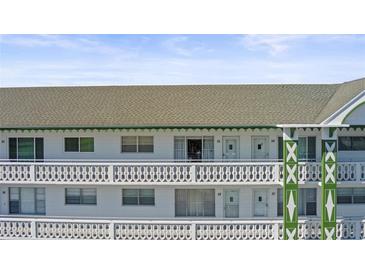 Condo building featuring a white exterior with green trim and decorative railings on multiple levels at 2468 Florentine Way # 52, Clearwater, FL 33763