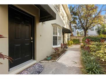 Inviting condo exterior featuring a private entrance, landscaped walkway, and lush greenery at 409 S Audubon Ave # 9, Tampa, FL 33609