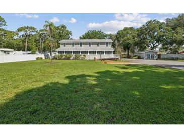 Large grassy yard with mature trees and a two-story house at 1055 Philippe Pkwy, Safety Harbor, FL 34695