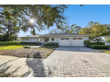 Ranch style home with two car garage, mature landscaping, and a brick paver driveway at 201 S Shore Crest Dr, Tampa, FL 33609