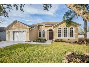 House exterior featuring a two-car garage and well-manicured lawn at 13029 Haverhill Dr, Spring Hill, FL 34609