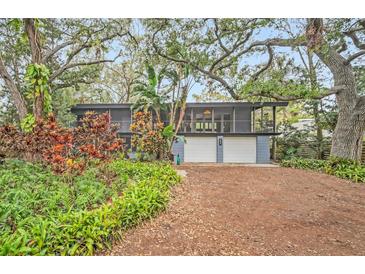 Mid-century modern home with lush landscaping and a two-car garage at 751 Pinellas Point S Dr, St Petersburg, FL 33705