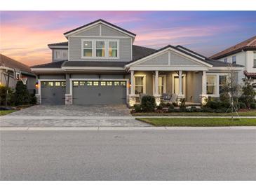 Two-story home with gray siding, three-car garage, and landscaping at 14215 Swiss Bridge Dr, Riverview, FL 33579
