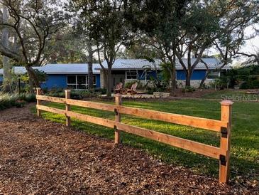 Ranch home with a wood fence and mature landscaping at 1880 Belleair Rd, Clearwater, FL 33764