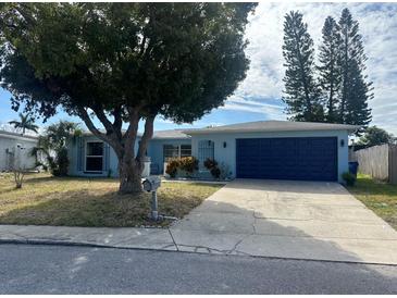 Ranch-style home with blue exterior, attached garage, and mature landscaping at 7524 Vienna Ln, Port Richey, FL 34668