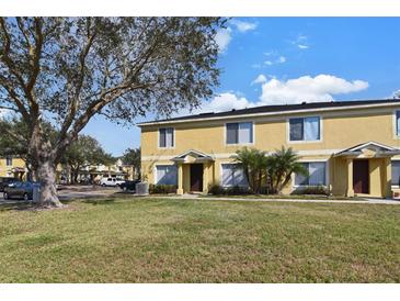 Two-story yellow townhome with grassy yard and trees at 10805 Keys Gate Dr, Riverview, FL 33579