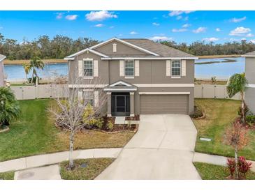 Two-story house with gray siding, attached garage, and landscaped yard at 16523 Myrtle Sand Dr, Wimauma, FL 33598