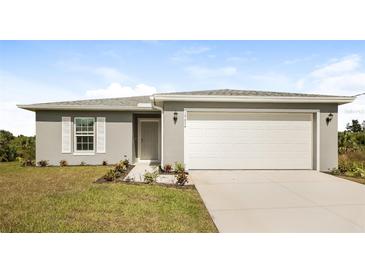 Gray house with white garage door, landscaping, and driveway at 19474 Strathcona Ave, Port Charlotte, FL 33954