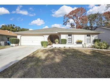 Charming single-story home with manicured lawn, an arched entryway, and attached two-car garage at 2603 Royal Ridge Dr, Spring Hill, FL 34606