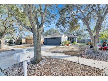 One-story house with gray garage door and mature trees in the front yard at 410 Pine Pointe Ct, Seffner, FL 33584