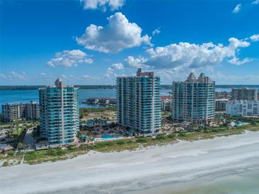 An aerial view showcasing beachfront condos with a pool, tennis courts, and ocean views at 1520 Gulf Blvd # 1602, Clearwater Beach, FL 33767