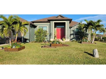 Green house with red door, landscaped yard, and palm trees at 8304 Antwerp Cir, Port Charlotte, FL 33981