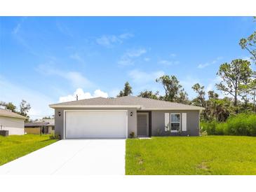 Newly constructed home with gray exterior, white garage door, and grassy lawn at 849 Haleybury St, Port Charlotte, FL 33948