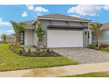 One-story home with gray siding, white garage door, and landscaped yard at 11482 Boundless Ter, Venice, FL 34293