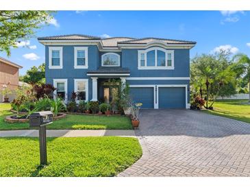 Two-story house featuring a blue exterior, paved driveway, and manicured landscaping at 12833 Darby Ridge Dr, Tampa, FL 33624