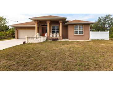 Single-story home with a tan stucco exterior, a large front yard, and a two-car garage at 3391 Knox Ter, Port Charlotte, FL 33948