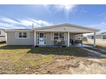 Gray house with covered porch, turquoise accents, and a yard at 4913 Lemonwood Loop, Holiday, FL 34690