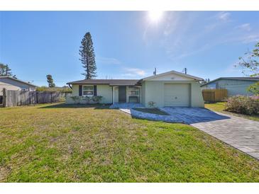 Updated light green house with a paved driveway and landscaped lawn at 6025 Florida S Cir, Apollo Beach, FL 33572