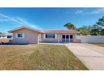 Brick ranch house with red tile roof, driveway, and well-maintained lawn at 7499 7Th N St, St Petersburg, FL 33702