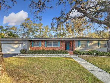 Brick ranch house with teal shutters, attached garage, and landscaped lawn at 2446 Belleair Rd, Clearwater, FL 33764