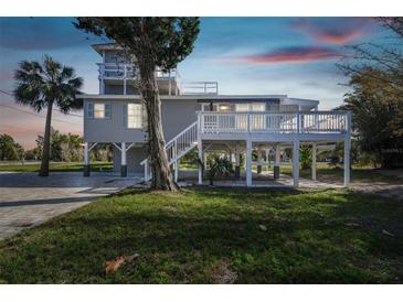 Charming stilt home featuring a large deck, lush greenery, and tropical landscaping at 3476 Tidewater Dr, Weeki Wachee, FL 34607
