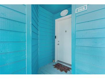 A charming turquoise condo entrance featuring a white door with the number 268 at 455 Alt 19 S # 268, Palm Harbor, FL 34683