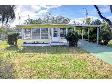Yellow single-story home with carport and landscaped lawn at 6021 Ridgewood Dr, Zephyrhills, FL 33542