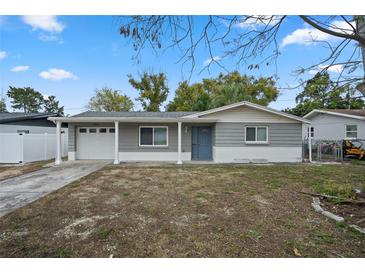 Gray house with white trim, attached garage, and a landscaped yard at 4925 Beacon Hill Dr, New Port Richey, FL 34652