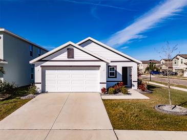 White house with brown accents, a two-car garage, and well-manicured landscaping at 682 Olive Conch St, Ruskin, FL 33570