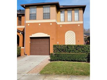 Two-story house with brown garage door and manicured hedges at 1028 Tullamore Dr, Wesley Chapel, FL 33543