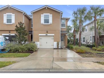 Tan two-story townhome with white garage door and landscaping at 17841 Althea Blue Pl, Lutz, FL 33558