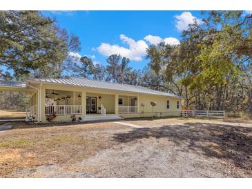 Ranch style home with metal roof, large porch, and spacious yard at 19256 Hidden Oaks Dr, Brooksville, FL 34604