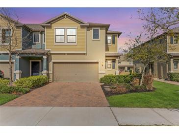 Two-story townhome with brick paver driveway and landscaped front yard at 16877 Red Brick Ln, Land O Lakes, FL 34638