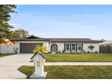 Newly renovated home with gray garage door and landscaped lawn at 2181 Wateroak N Dr, Clearwater, FL 33764