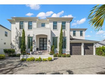 Two story home featuring a manicured lawn, brick driveway, and a two car garage at 2502 S Dundee St, Tampa, FL 33629