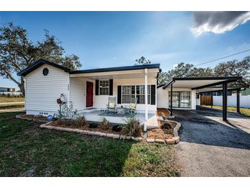 Charming single-story home with a red front door, covered porch with seating, and a convenient carport at 6254 Pershing Ne St, St Petersburg, FL 33702