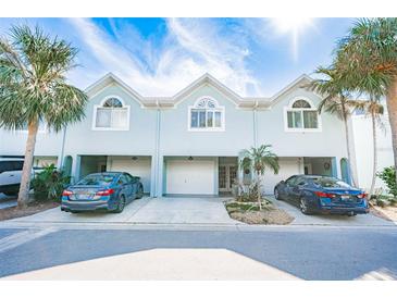 Three-unit townhouse building, light teal exterior, two-car garages, and landscaping at 657 Garland Cir, Indian Rocks Beach, FL 33785