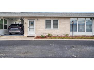 Front view of a light-colored, single-story home with carport and landscaping at 12400 Park Blvd # 206, Seminole, FL 33772