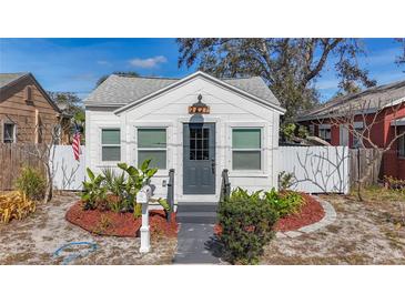 Charming white cottage with gray door, landscaping, and fenced yard at 2427 10Th S Ave, St Petersburg, FL 33712