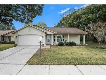 Brick ranch home with attached garage, and a well-manicured lawn at 10504 Tapestry Dr, Port Richey, FL 34668