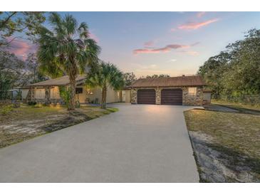 House exterior featuring a two-car garage and a spacious driveway at 18801 Orange Hill Dr, Hudson, FL 34667