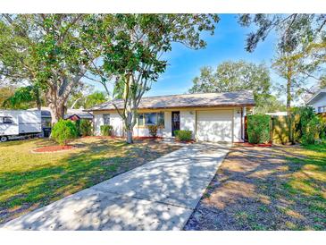 Cute ranch home with a paved driveway, mature landscaping, and a detached garage at 21 Belle Meade Cir, Largo, FL 33770